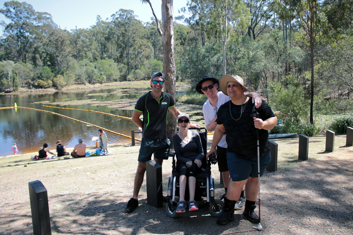 Group of people by the lake, some in wheelchair or with walking cane